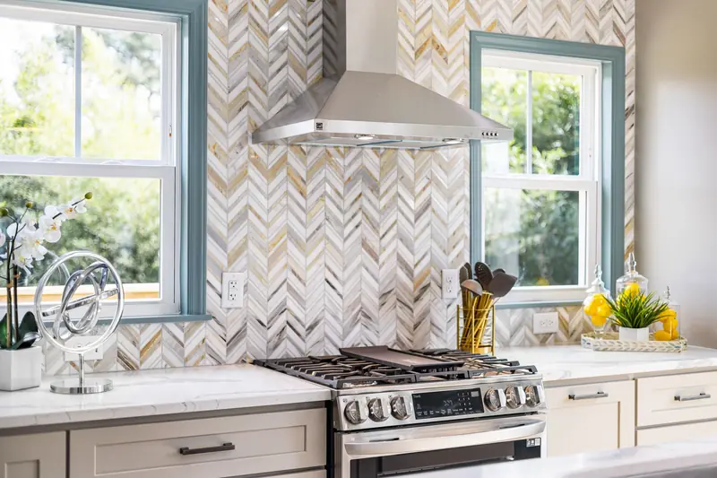 Herringbone stone tile backsplash behind a range