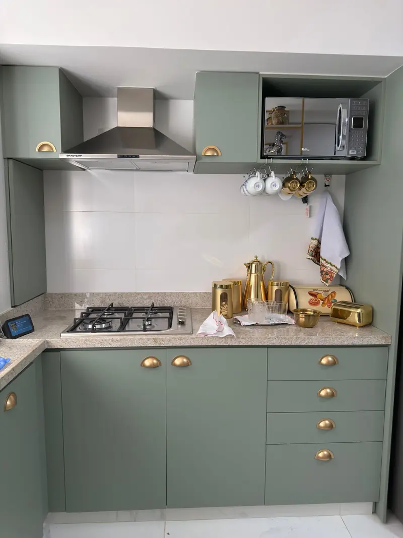 Sage green Shaker cabinet doors and drawers with brass knobs