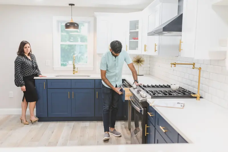 Installer checking a drawer in a finished kitchen while the homeowner watches
