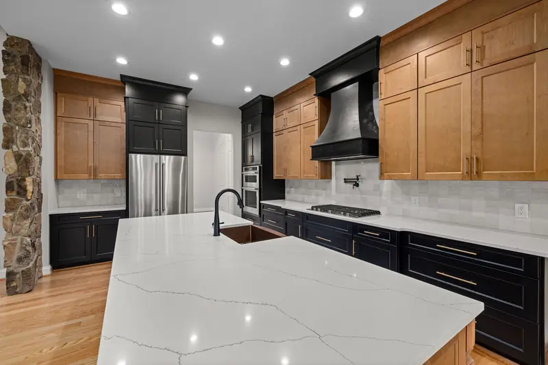 Wood and black cabinets around a white quartz island