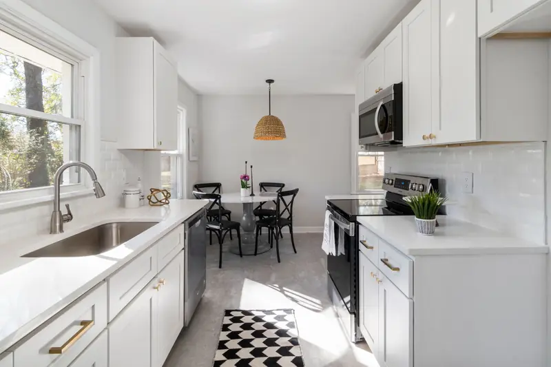 Compact galley kitchen with white cabinets and a window over the sink