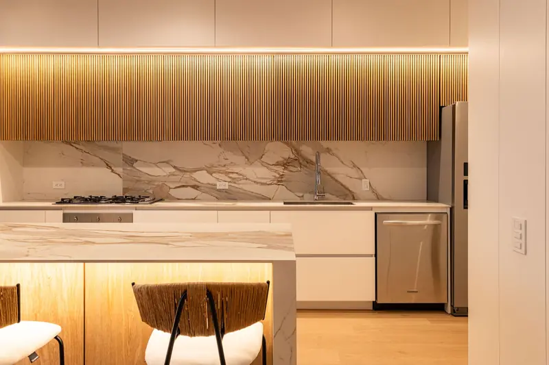 Modern kitchen with flat-panel cabinets, wood slat uppers and a marble slab backsplash