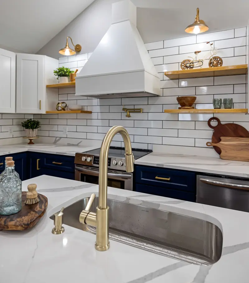 Navy island with a brass faucet and white quartz countertop