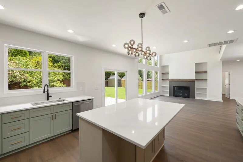 Open kitchen with sage green cabinets, a quartz island and a view to the living room