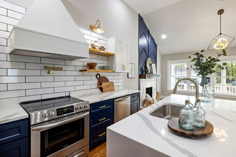 Two-tone kitchen with navy lower cabinets, white uppers and brass accents