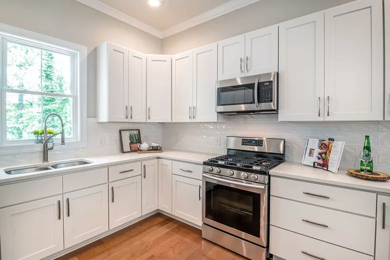 White Shaker cabinets with stainless appliances and wood floors