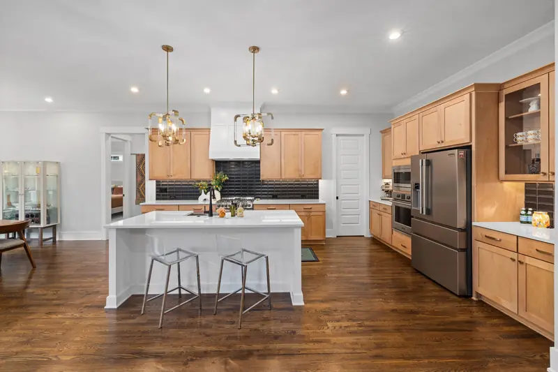 Warm wood cabinets around a white island with pendant lights