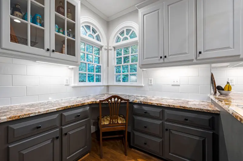 Under-cabinet lighting above a granite countertop and gray cabinets
