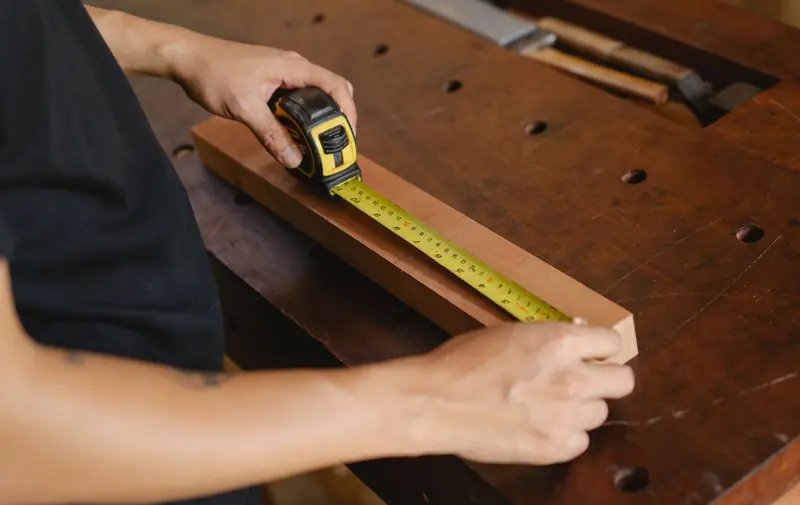 Tape measure held against a wooden board